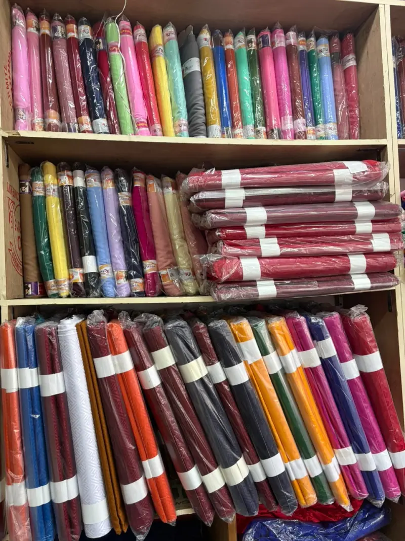 Shelves stocked with rolls of suiting and shirting fabric in a range of colours