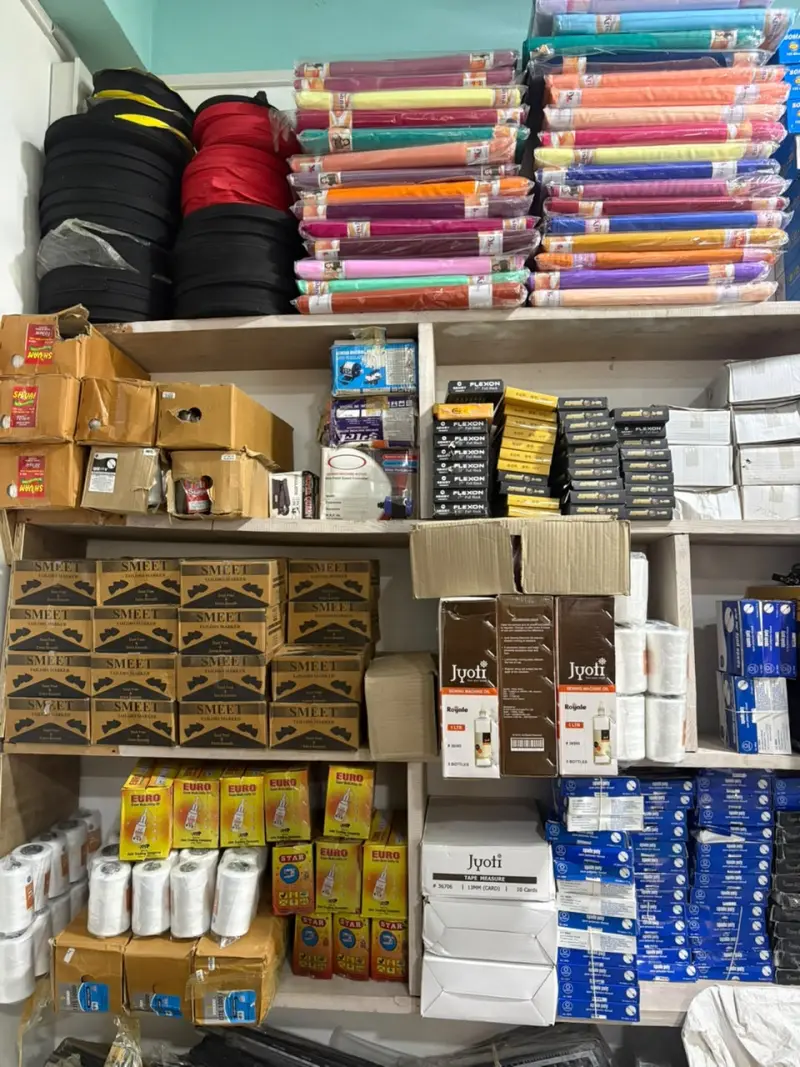 Shelves of tailoring notions including chalk markers, tapes, threads, and machine oil